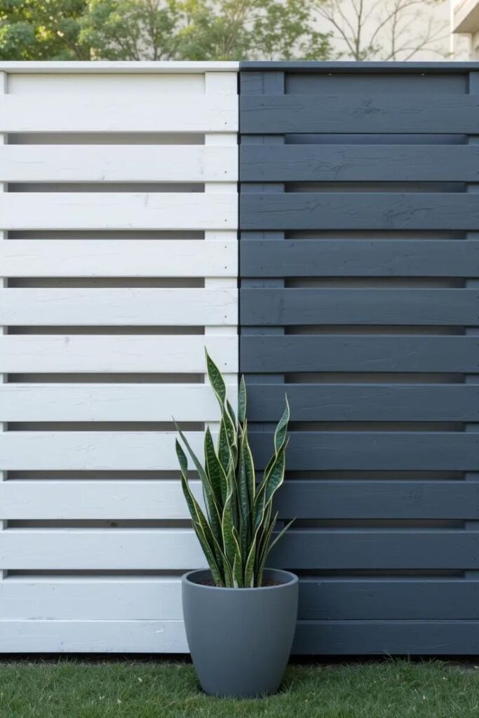 A backyard fence made from wooden pallets, painted in a two-tone design.