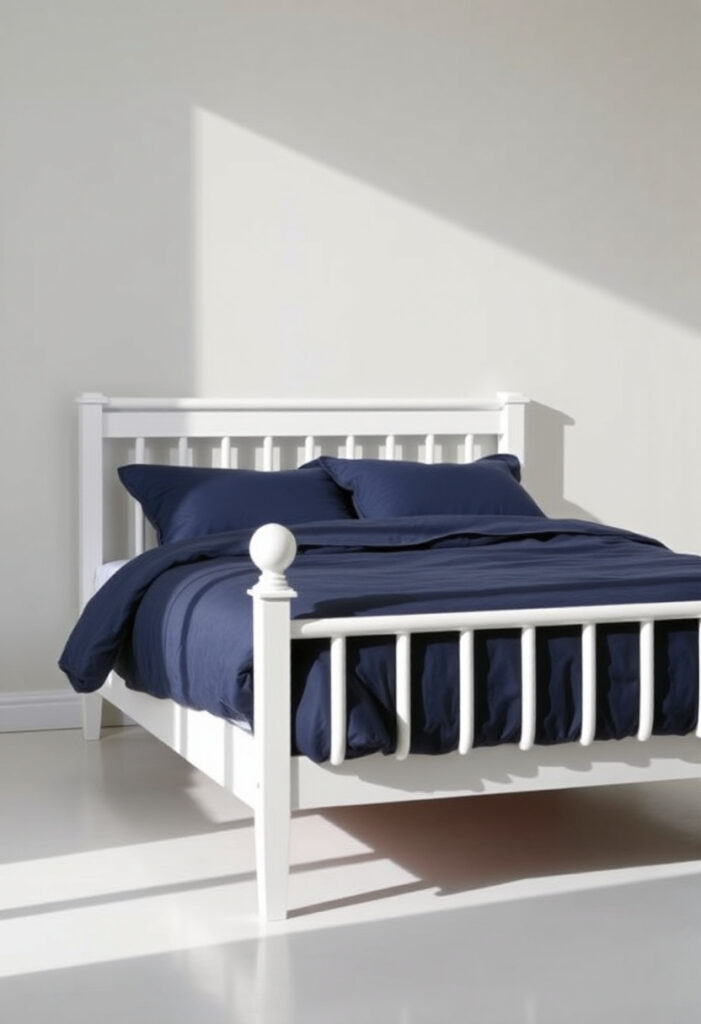 A white wooden bedframe with simple clean lines, dressed with navy blue bedding.