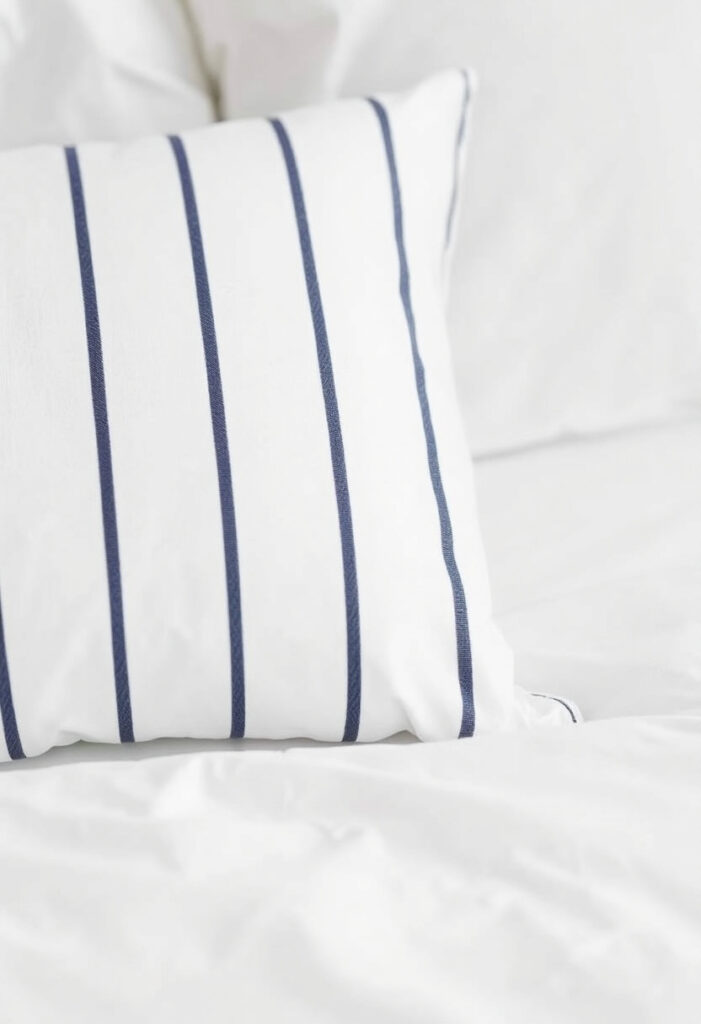 a white bed pillow with navy and white thin stripes.