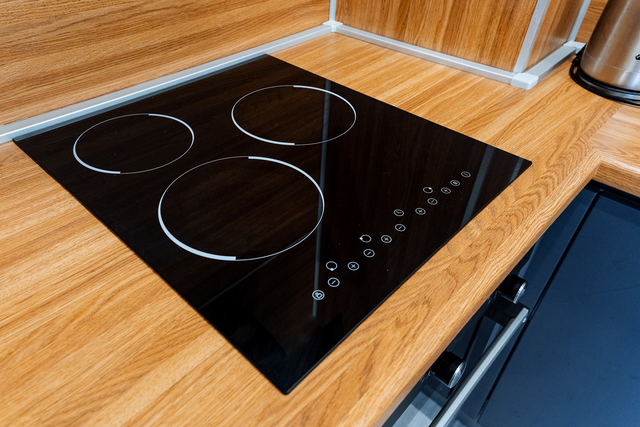 A stove cooktop is placed on a wooden countertop in a kitchen.