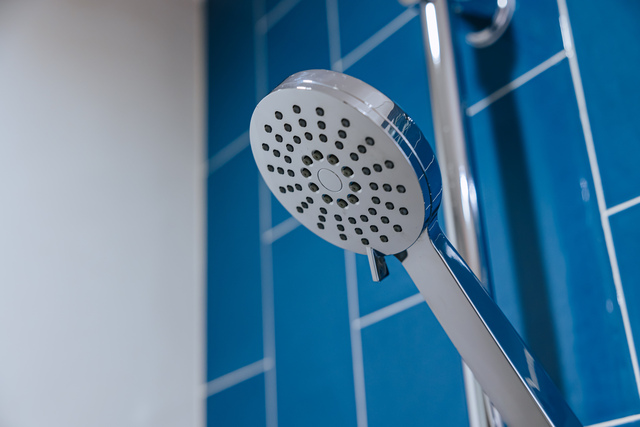Chrome Shiny Dry Shower Head In Bathroom Blue Wall Background
